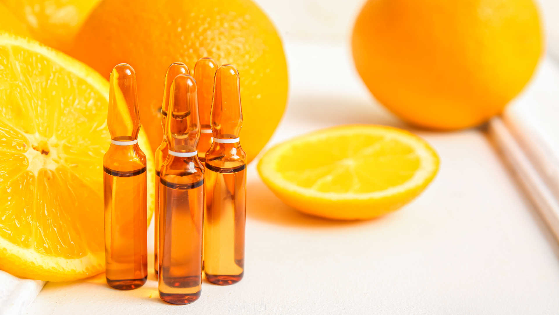 Vitamin C ampoule surrounded by oranges